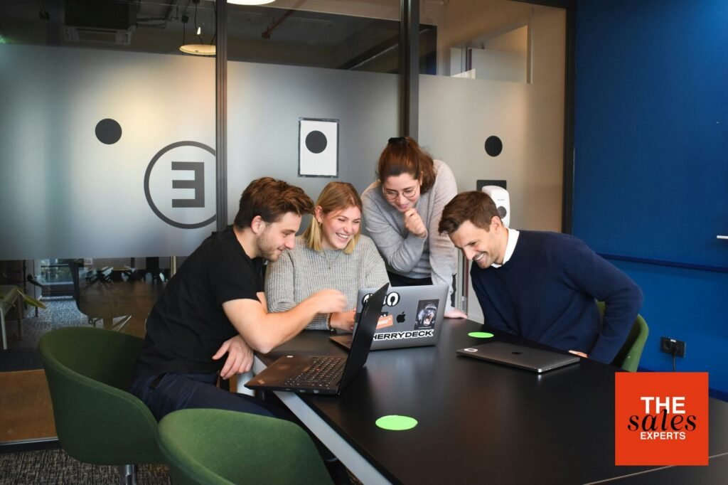 Recruitment team collaborating around laptops in an office