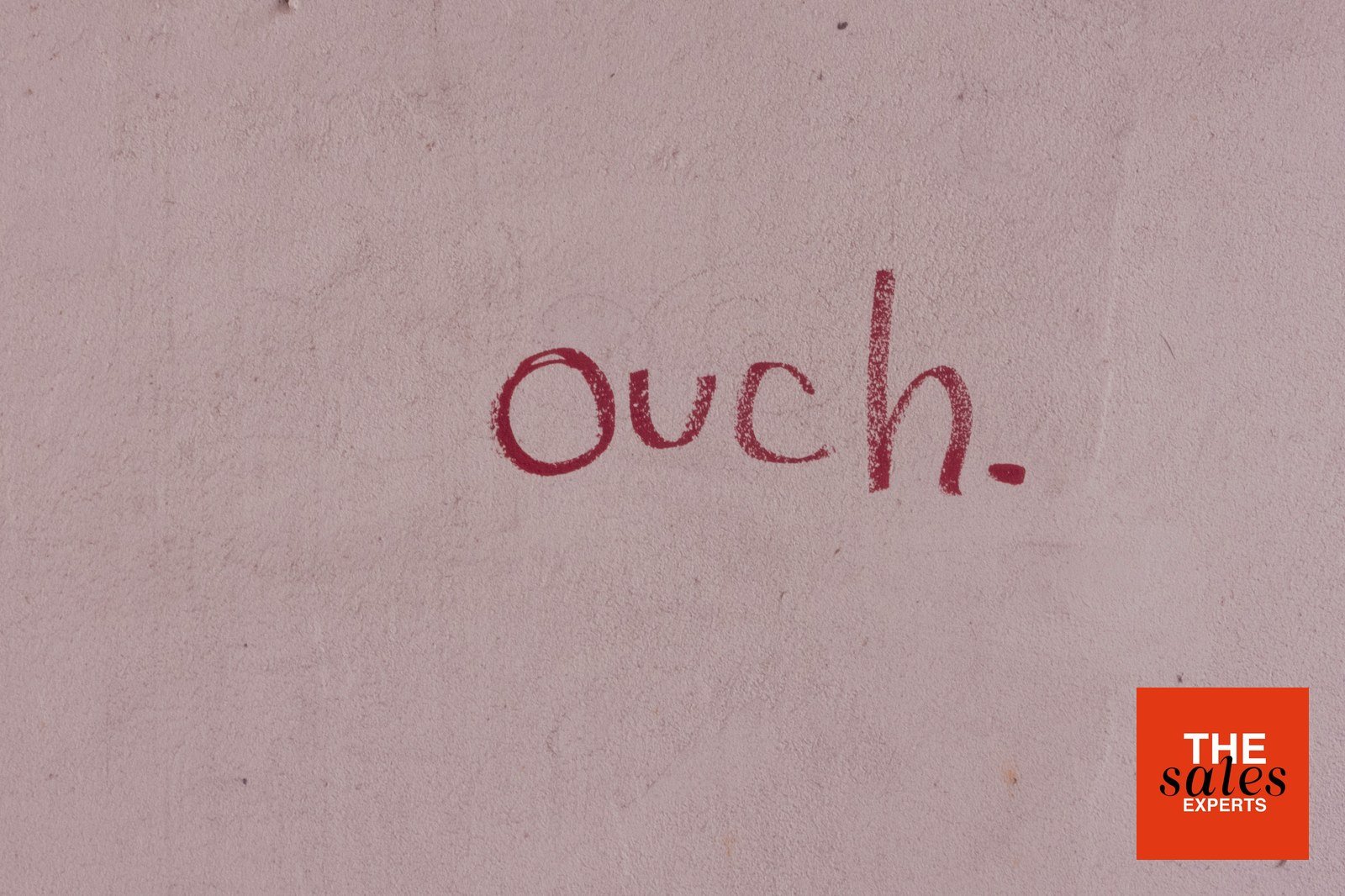 Ouch written on a wall, representing sales objections